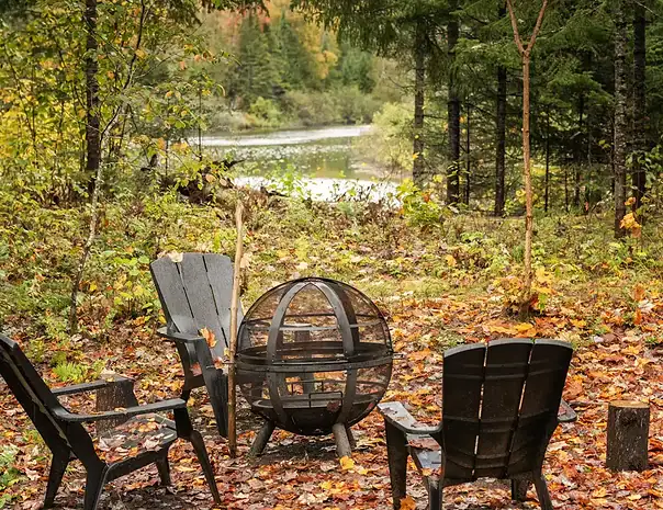 Chalet haut de gamme avec expérience thermale complète digne d'un spa nordique privé à St-Côme dans Lanaudière - Site de feu extérieur à l'automne avec vue sur la rivière